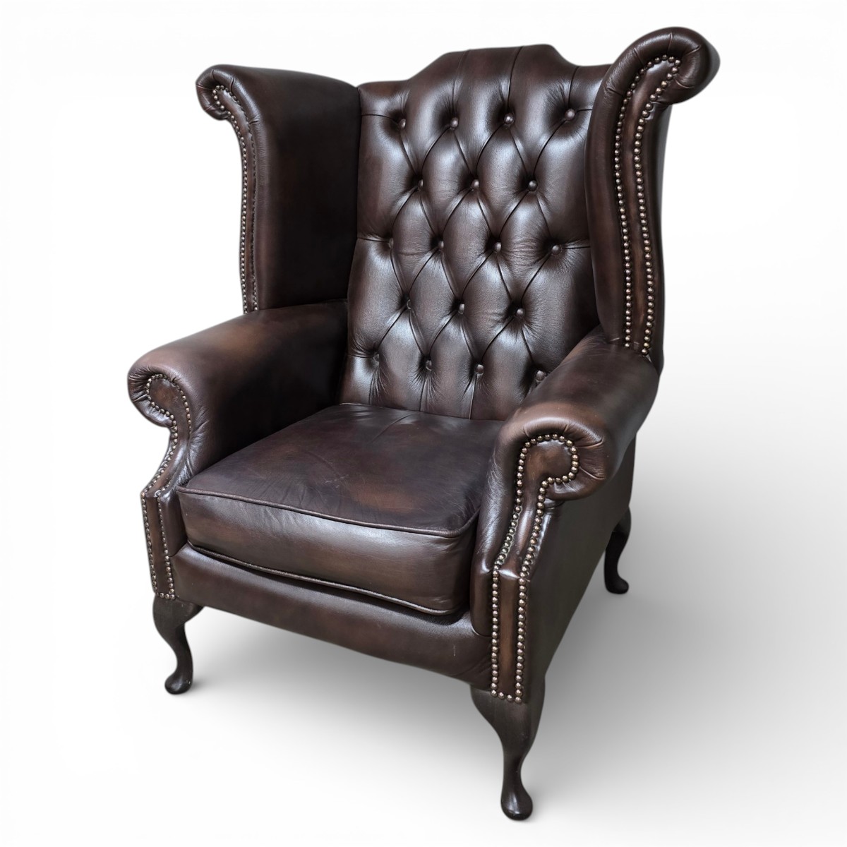 Second hand Chesterfield wingback armchair in oxblood leather, with high winged back, deep button-tufting, and studded nailhead trim.