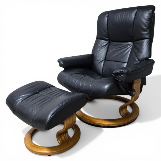 Ekornes Stressless Mayfair Recliner Armchair and Footstool in black leather, featuring a classic curved wooden base and plush segmented cushioning
